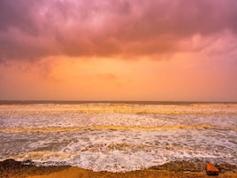 Una playa con olas y un cielo nublado.