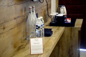 Un mostrador de recepción de madera con un cartel de bienvenida, botellas de agua y una cafetera.