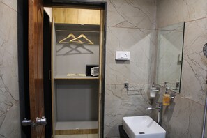 Un baño con puerta de madera, lavamanos blanco, espejo y un perchero para toallas.