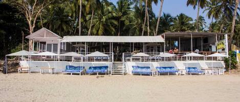 A beachside building with multiple covered seating areas and a bar.