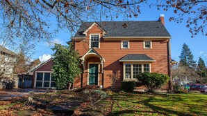 A two-story house with a front porch, a garage, and a well-maintained lawn. - Updated Campus Home (Eugene)