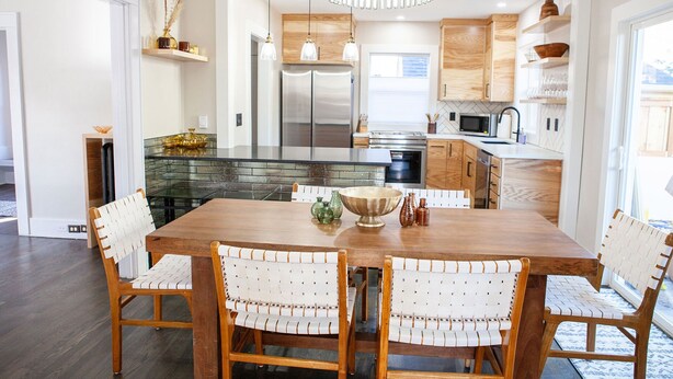 A modern kitchen with a central island, wooden cabinets, and a dining area with a wooden table and chairs. - Updated Campus Home (Eugene)