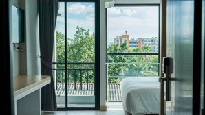 Une chambre d’hôtel avec un balcon, un lit, un bureau et une télévision.