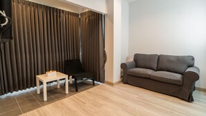 Un salon moderne avec un canapé gris, un fauteuil noir et une petite table blanche.