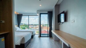 Une chambre d’hôtel avec deux lits, une télévision et un balcon donnant sur la ville.