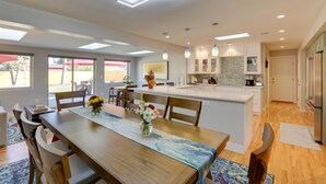 A modern kitchen with a central island, white cabinetry, and pendant lighting. - Saulsbury Guest House & Wellness Retreat w/ Sauna (Wheat Ridge)