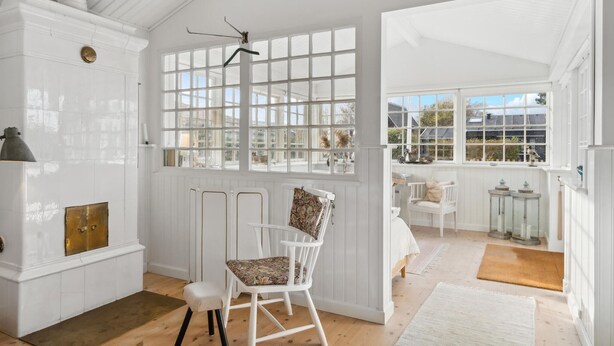 A bright, white room with large windows, a white chair, and a small table. - Gorgeous home in Assens with kitchen (Assens)