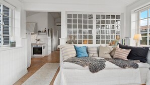 A spacious living area with a large window, a kitchen in the background, and a cozy seating area with a patterned throw blanket. - Gorgeous home in Assens with kitchen (Assens)