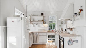A kitchen with white cabinetry, a wooden floor, and a window with a view of greenery. - Gorgeous home in Assens with kitchen (Assens)