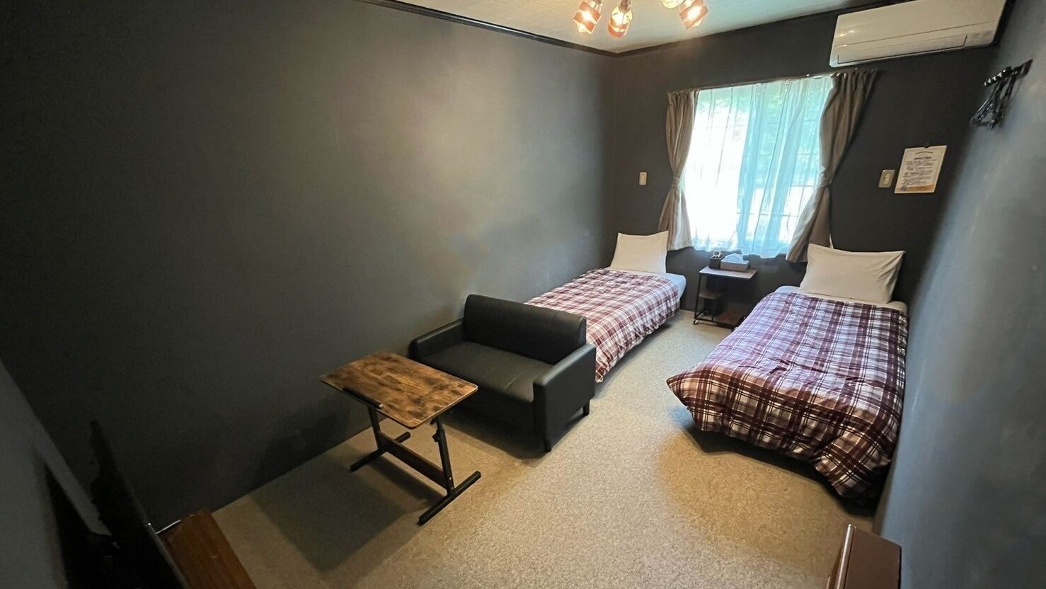 A small, compact room with two beds, a sofa, and a small table.