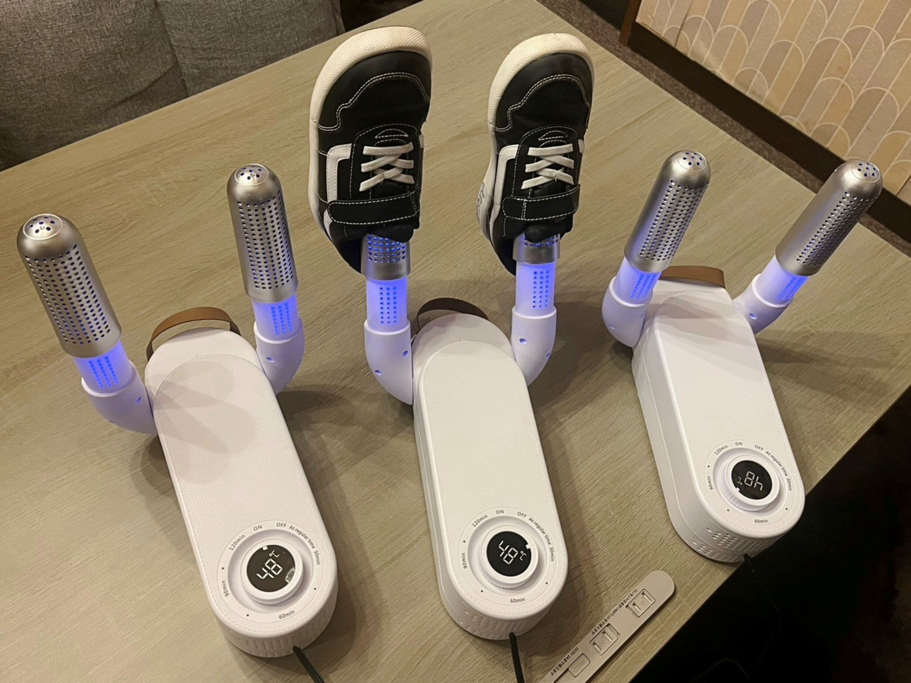 Cuatro altavoces portátiles blancos con luces azules sobre una mesa de madera.