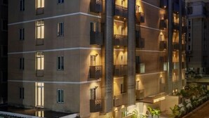 A multi-story hotel with balconies, a covered entrance, and a landscaped area with small trees. - Eminent Suites & Apartments (Hyderabad)