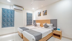 A modern hotel room with two beds, a wooden headboard, a nightstand, and artwork on the walls. - Eminent Suites & Apartments (Hyderabad)