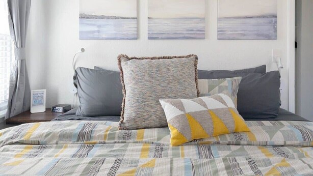 Une chambre à coucher avec un lit, des oreillers et une vue sur la mer par la fenêtre.