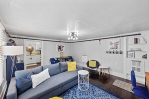 En moderne stue med en grå sofa, et rundt hvidt sofabord og en blåstribet måtte.