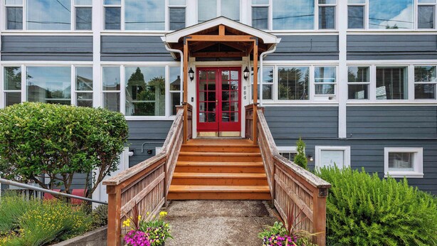 A building with a red door, wooden stairs, and a small porch.