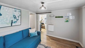 Un salon avec un canapé bleu, un luminaire au plafond et une carte encadrée accrochée au mur.