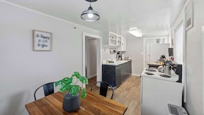 Une cuisine compacte comprenant un coin repas, un petit îlot central et un luminaire fixé au mur.