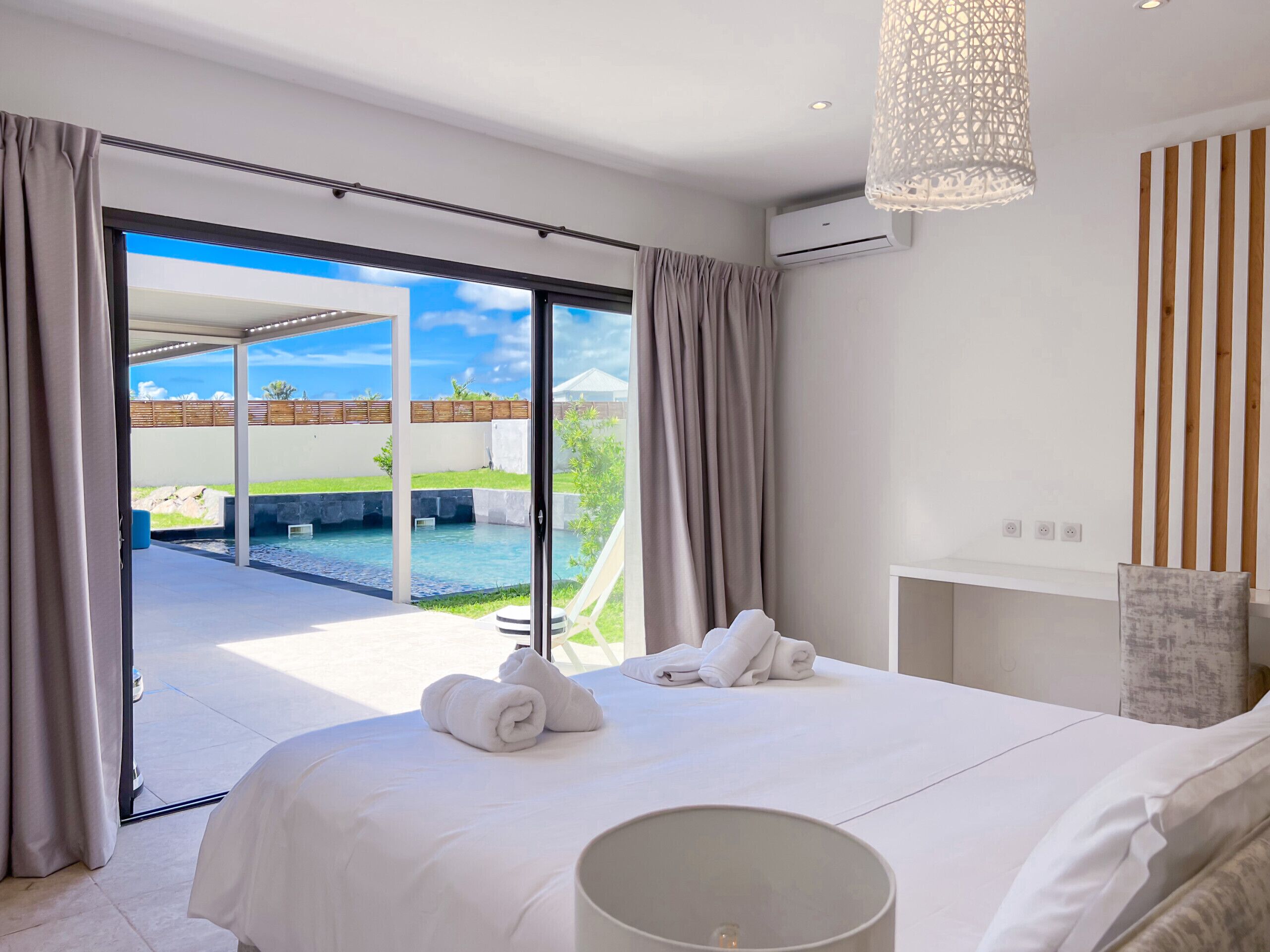 A hotel room with a large bed, a view of a swimming pool, and a ceiling light fixture.
