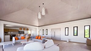 Un amplio salón con un sofá moderno, una mesa de centro y una cocina al fondo.