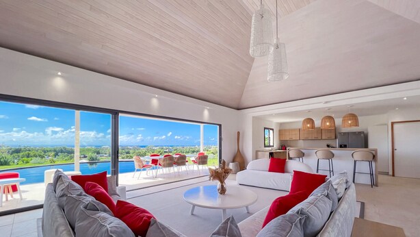 Un'ampia zona living con una grande finestra che si affaccia su un panorama suggestivo, una cucina moderna e una sala da pranzo con sedie rosse.