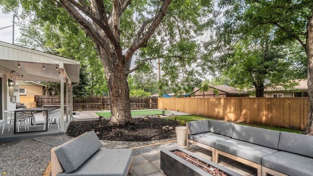 A backyard with a covered patio, outdoor seating, a fire pit, and a large tree. - Game Room- Hot Tub- Sauna & Projector! (Arvada)