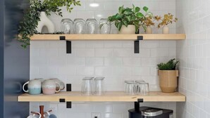 A kitchen with two wooden shelves holding glassware, a plant, and a vase. - Spacious home with Game Room, Hot Tub & Sauna! (Westminster)