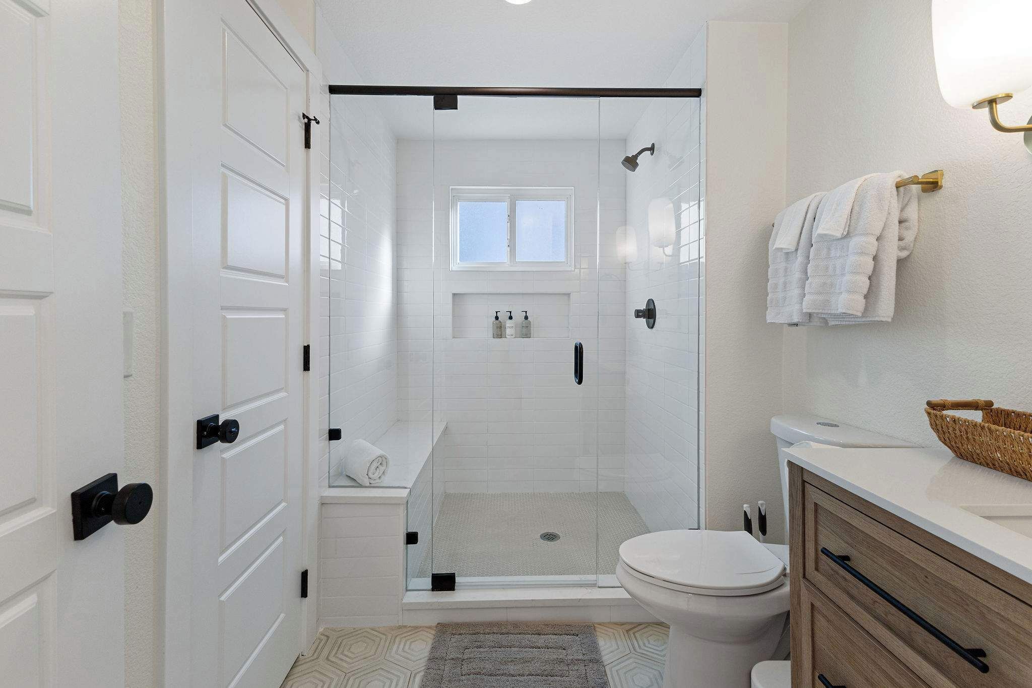 Een moderne badkamer met een douchecabine, een toilet en een wastafel met een mand.