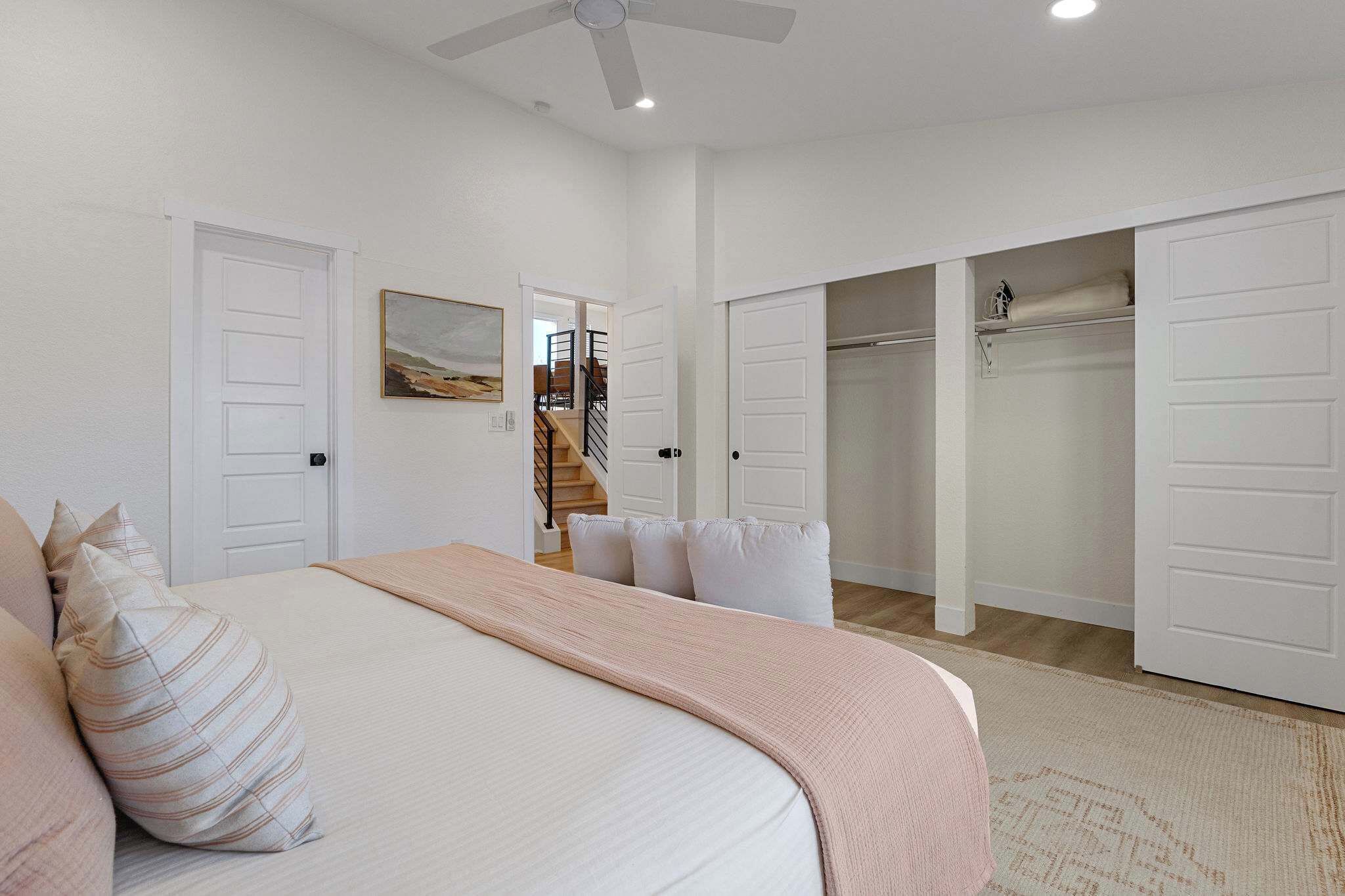 A bedroom with a bed, a ceiling fan, and a closet with a mirror.