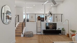 A modern living room with a staircase, a television, and a dining area. - Spacious home with Game Room, Hot Tub & Sauna! (Westminster)