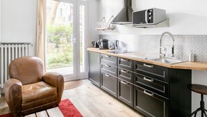 Une cuisine moderne équipée d’un four à micro-ondes, d’une machine à café et d’un évier. On y trouve également un fauteuil en cuir et un tapis rouge.