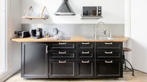 Une cuisine moderne dotée d’un plan de travail en bois, de meubles noirs, d’un évier en acier inoxydable et d’un four à micro-ondes.