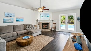 A living room with a fireplace, a sofa, a coffee table, and a ceiling fan.
