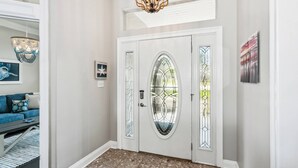 A foyer with a white door, a chandelier, a blue sofa, and a rug.