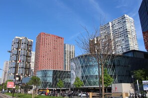 A modern urban street with high-rise buildings, including a distinctive red building and a glass structure with a geometric pattern. - Studio Photo face au Parc des Expositions (Paris)