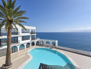 Un bâtiment moderne doté d’une piscine et offrant une vue sur la mer.