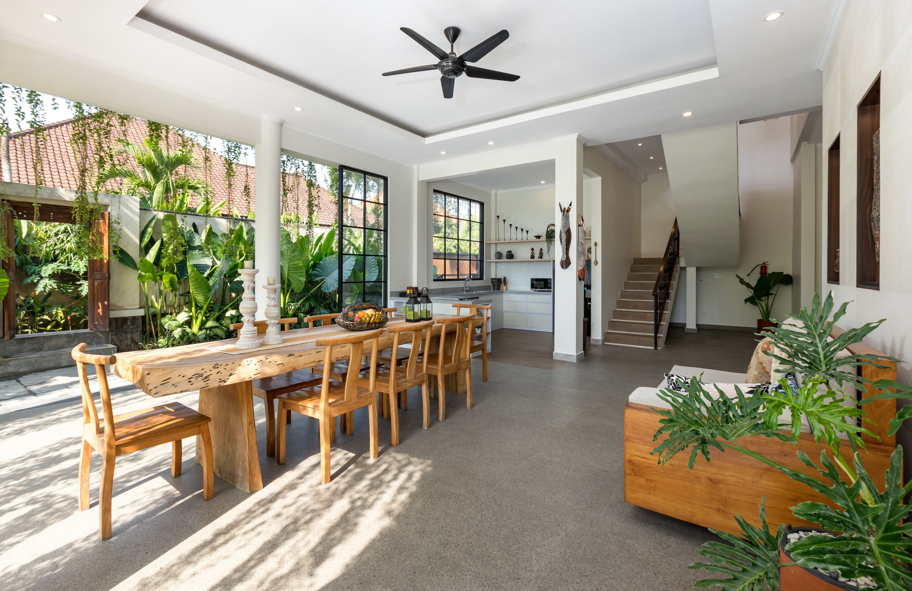 A spacious, modern kitchen with a dining area, large windows, and a ceiling fan.