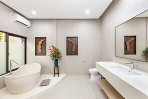Une salle de bain moderne avec une baignoire sur pieds, un grand miroir et un lavabo blanc.