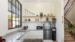 Une cuisine moderne dotée de plans de travail en granit, d’un réfrigérateur en acier inoxydable, d’un four à micro-ondes et d’un îlot central avec une plaque de cuisson en verre.