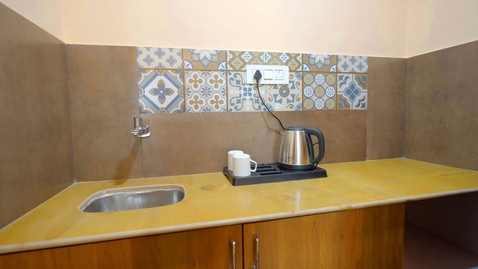 Una cucina compatta con lavandino, bollitore e macchina da caffè sul piano di lavoro.
