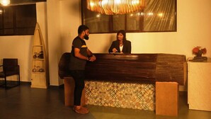 Un mostrador de recepción con encimera de madera y baldosas estampadas. A la izquierda hay una silla y un adorno decorativo sobre el mostrador.