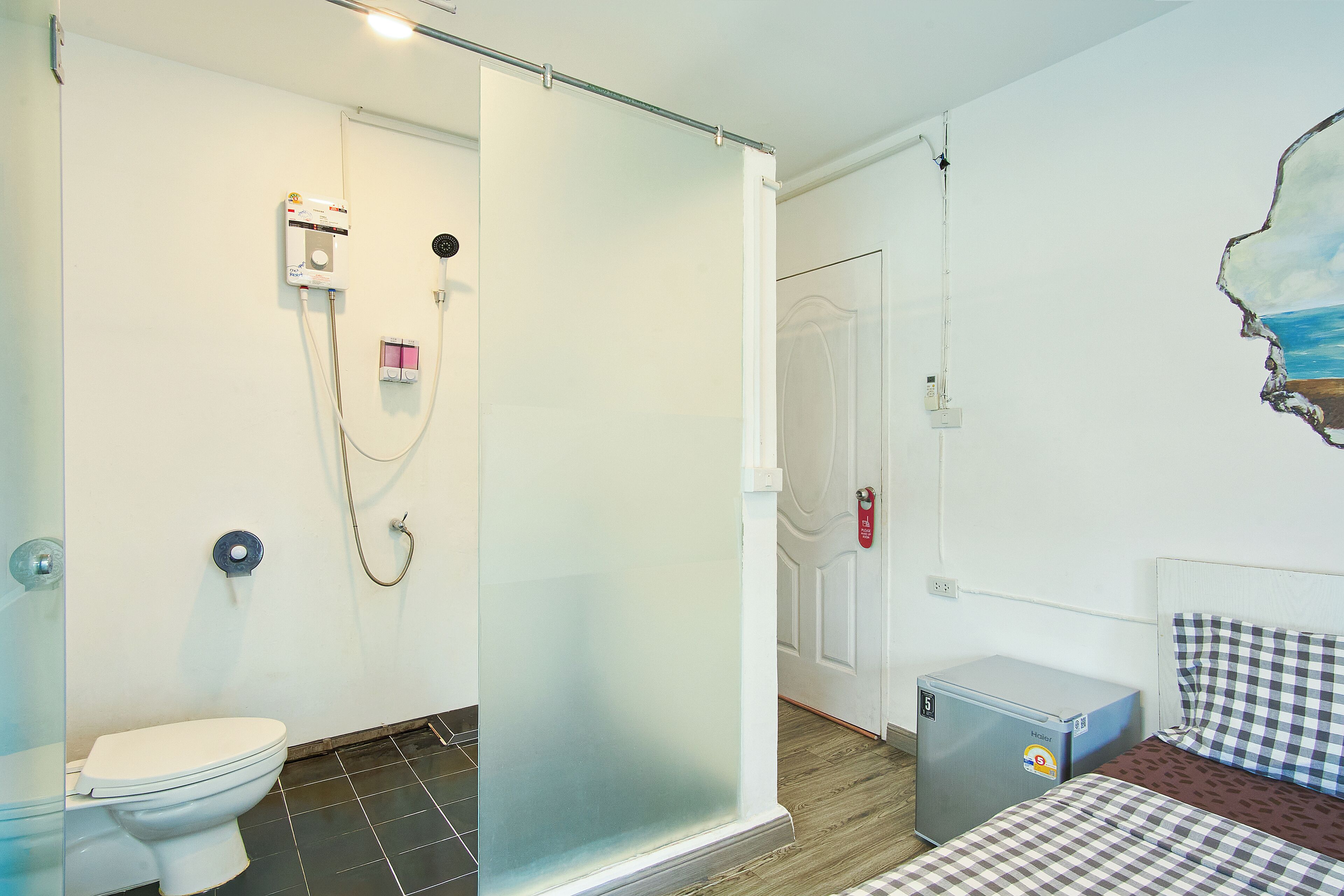 A bathroom with a toilet, a shower, and a glass partition.
