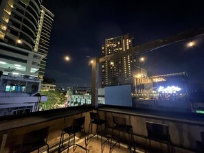 A rooftop terrace with chairs and a view of city buildings at night. - comfy crib hostel  (Bangkok)