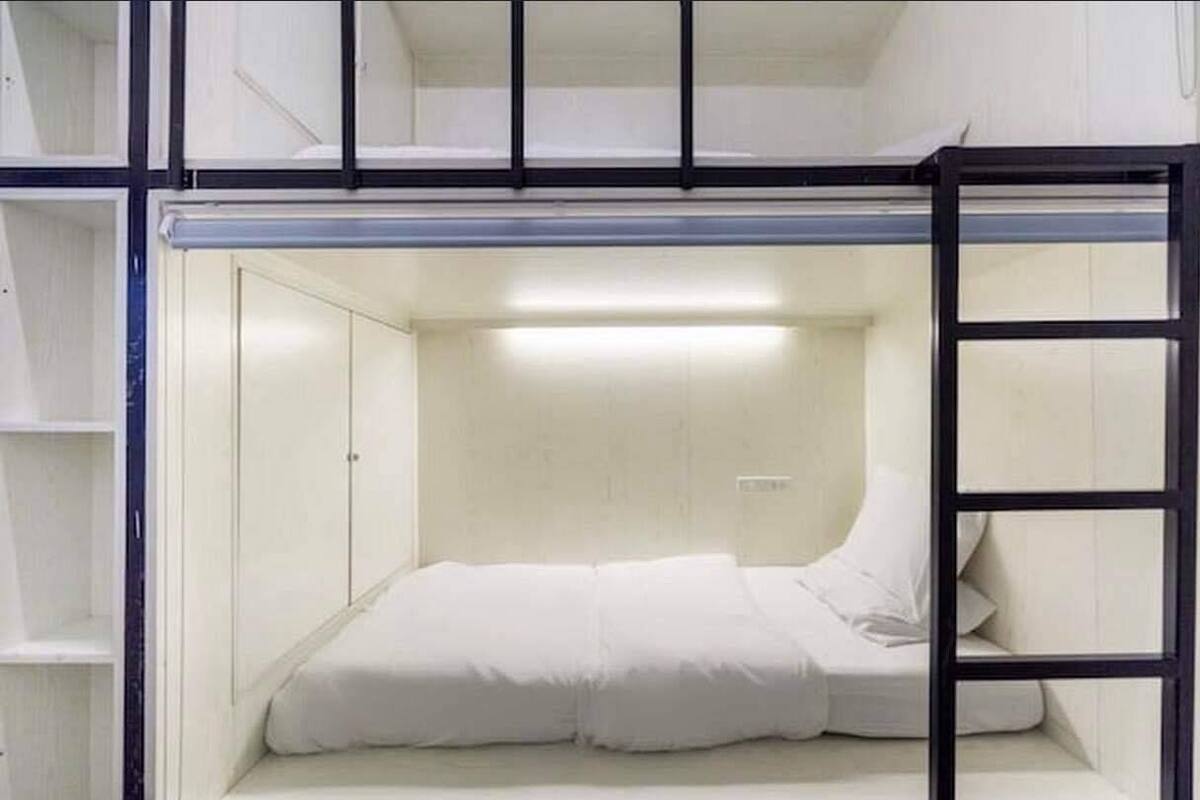 A bunk bed room with a ladder, a single bed, and a wardrobe.