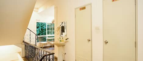 A hotel hallway with a staircase, a sink, and two doors labeled 'TOILET'.