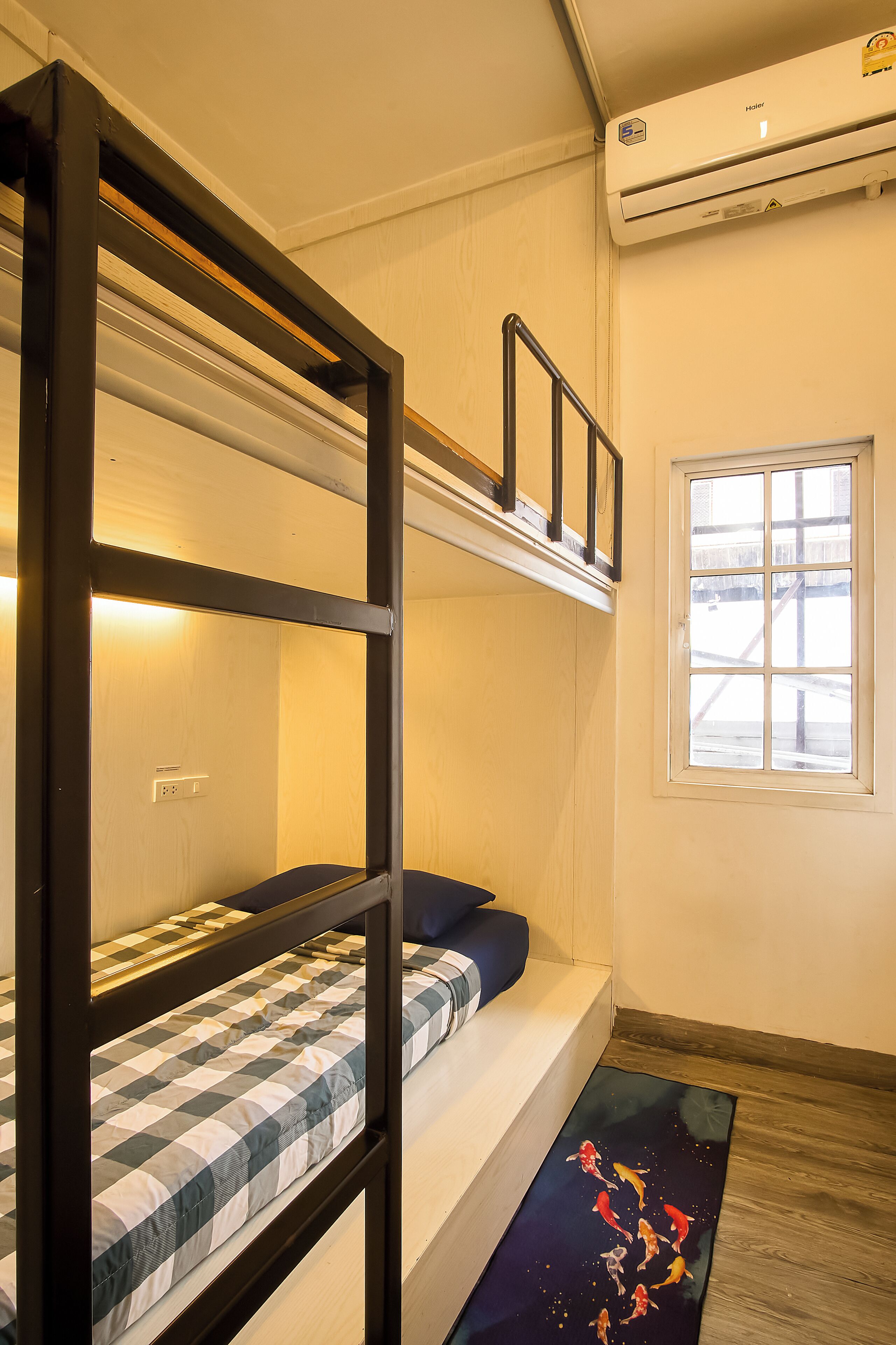 A bunk bed room with a window and an air conditioning unit.