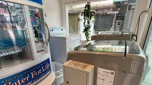 A water dispenser with a blue and white design, a small cabinet, and a window with a view of the outside. - comfy crib hostel  (Bangkok)