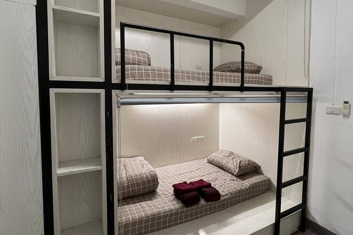 A bunk bed with a ladder, a shelf unit, and a small bedside table.