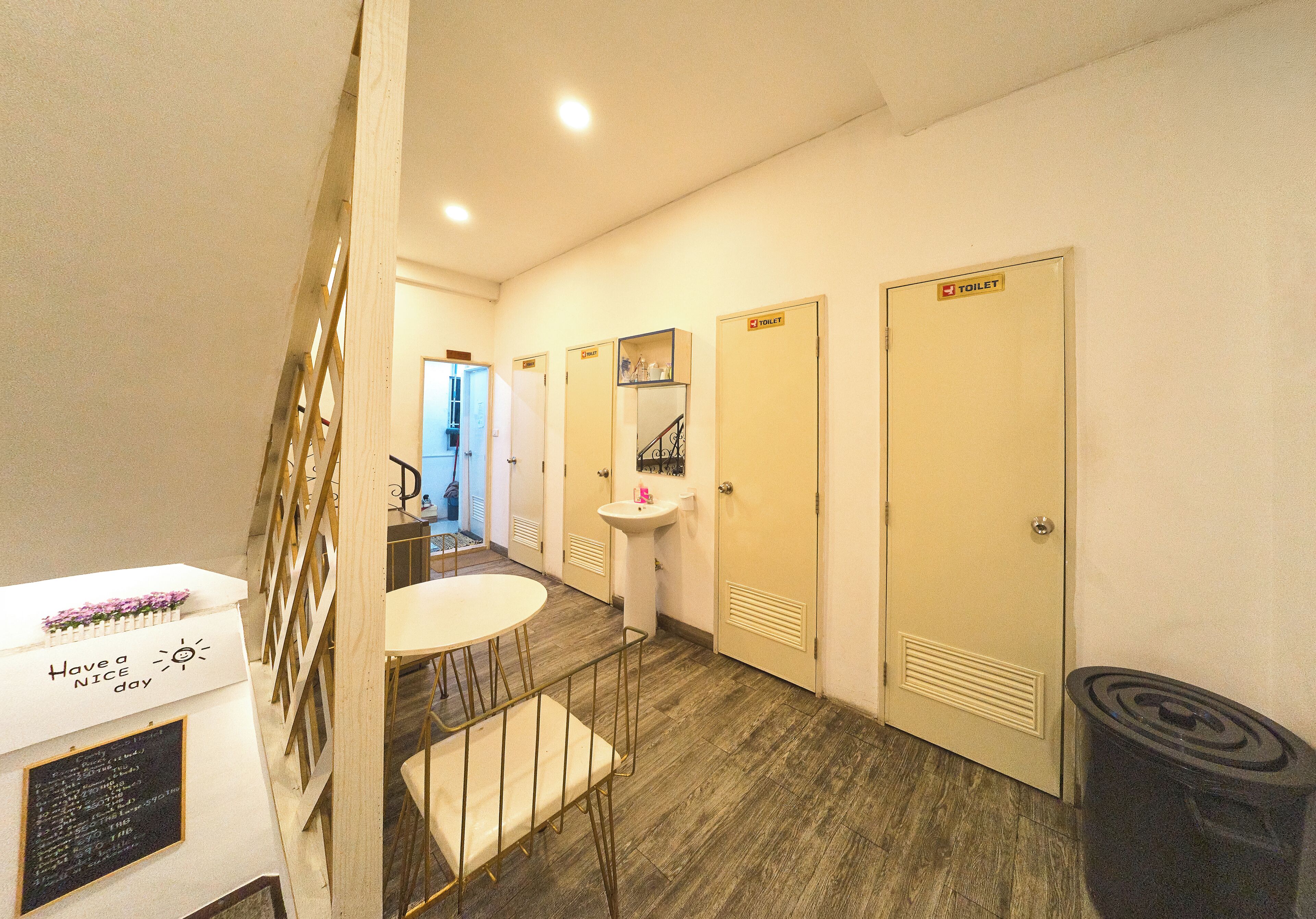 A hotel room with a staircase, a small table with chairs, a sink, and three doors marked 'TOILET'.