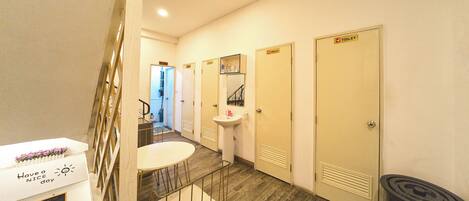 A hotel room with a staircase, a small table with chairs, a sink, and three doors marked 'TOILET'.